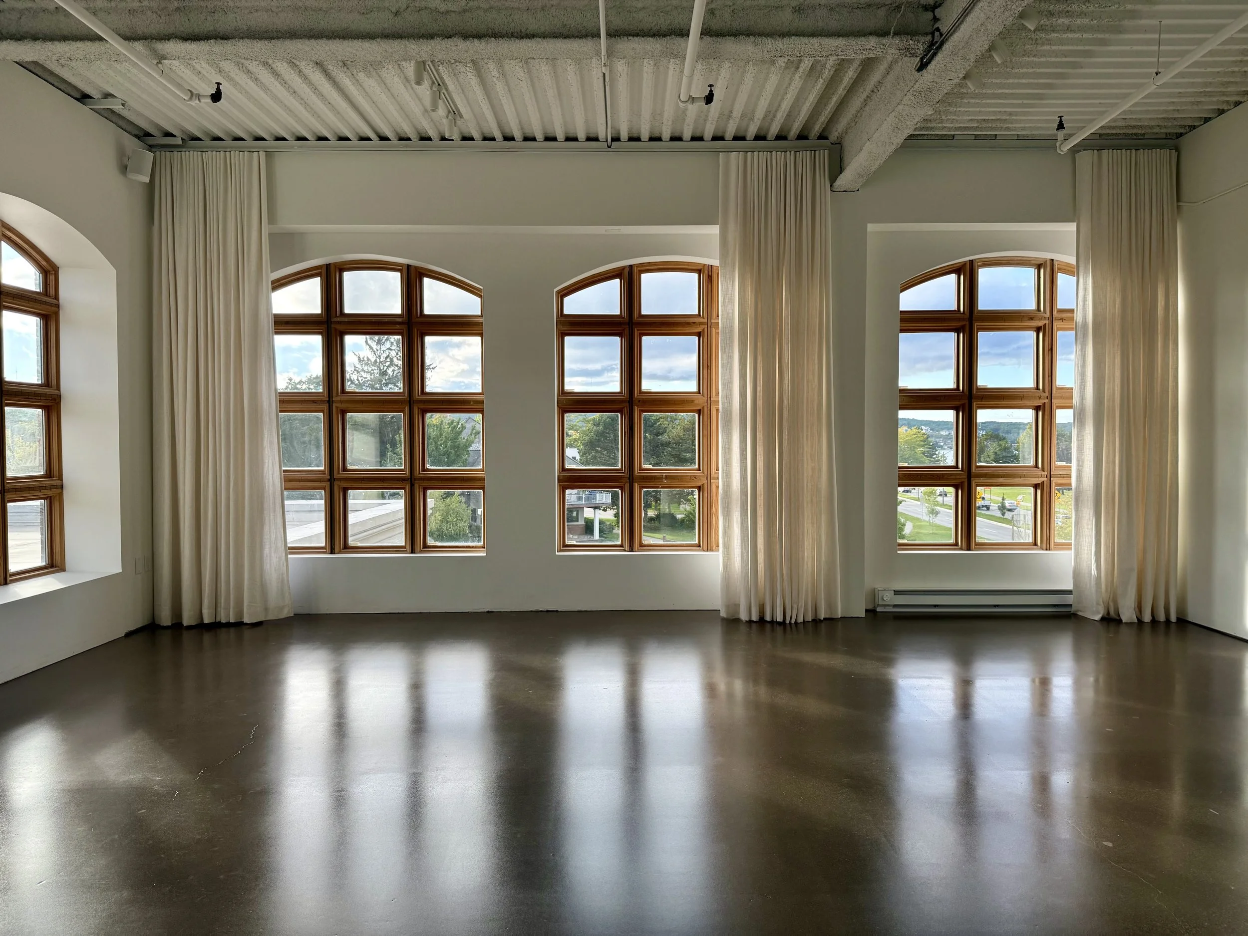 Photo of an empty photo studio space with natural light and large wooden arched windows
