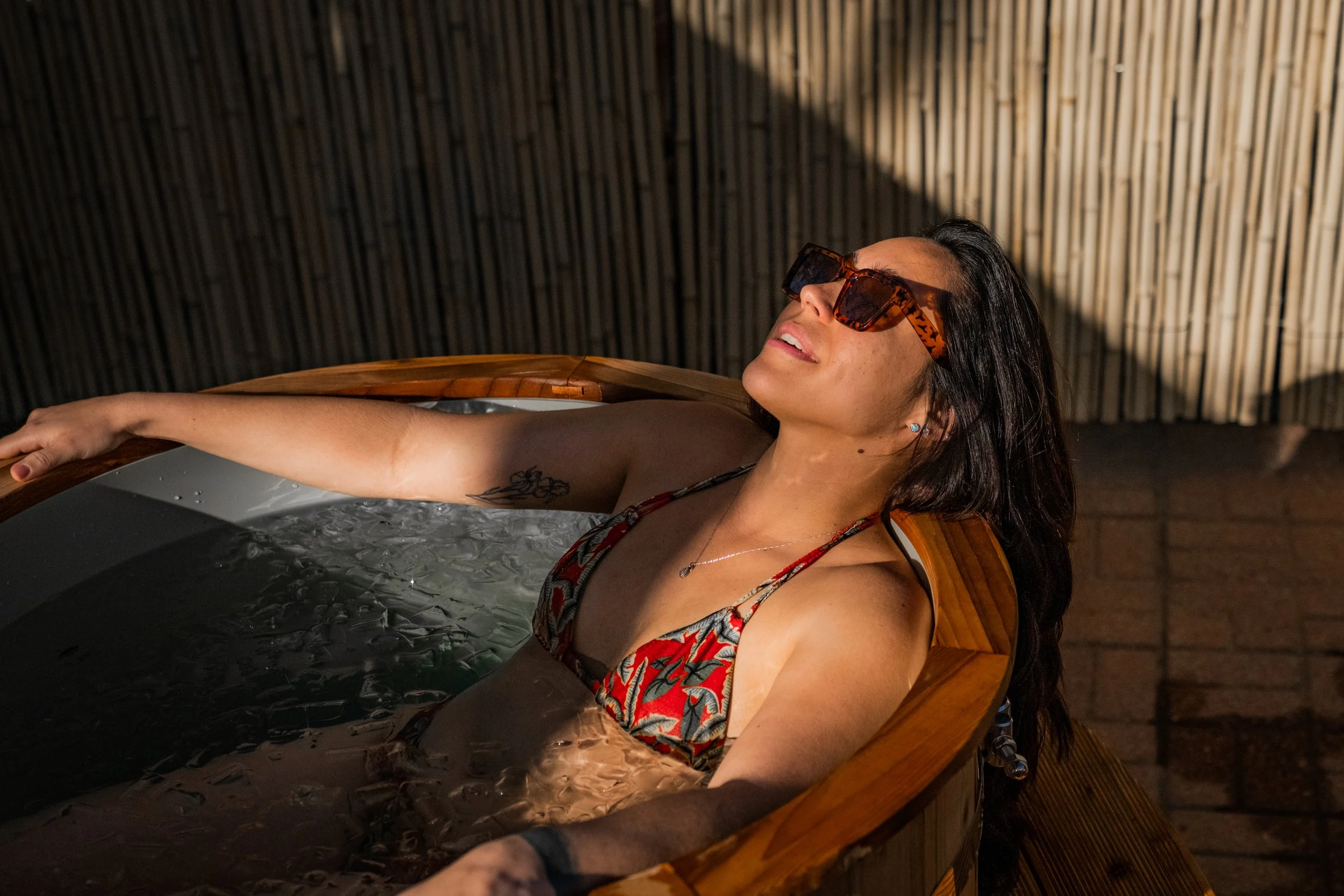 Woman relaxing in a wooden cold plunge tub, after using Denver sauna near me.