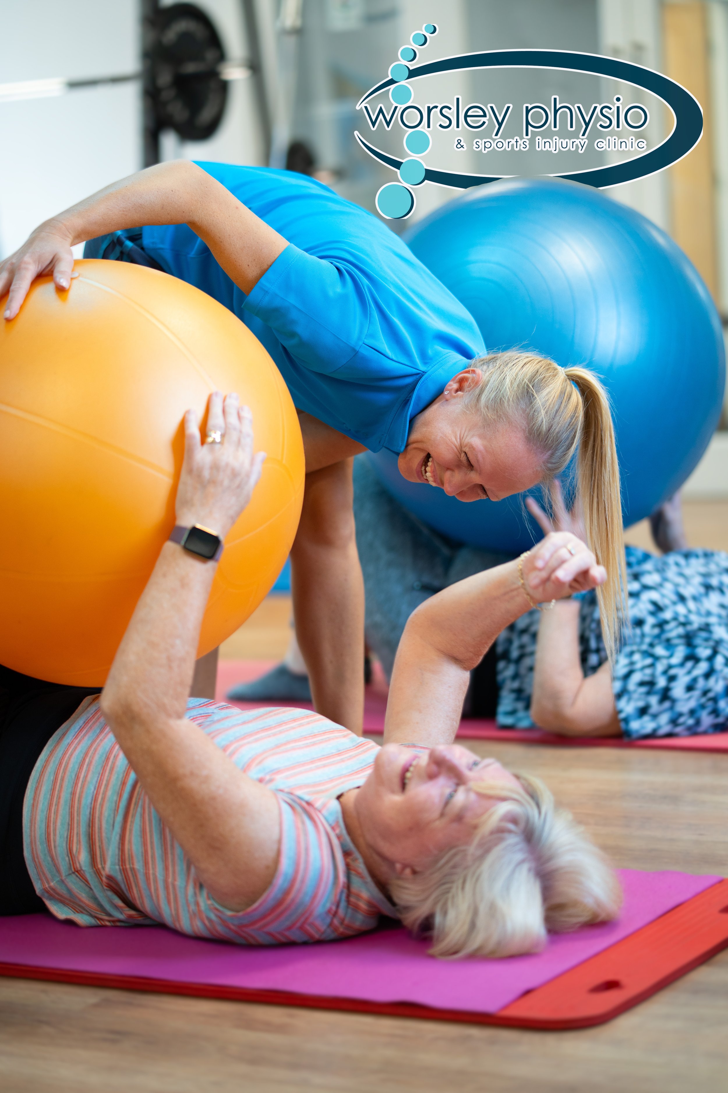 Elderly women exercising with orange and blue stability balls, supervised by a physical therapist, in a fitness or rehabilitation center. Professional photography. Physio campaign.