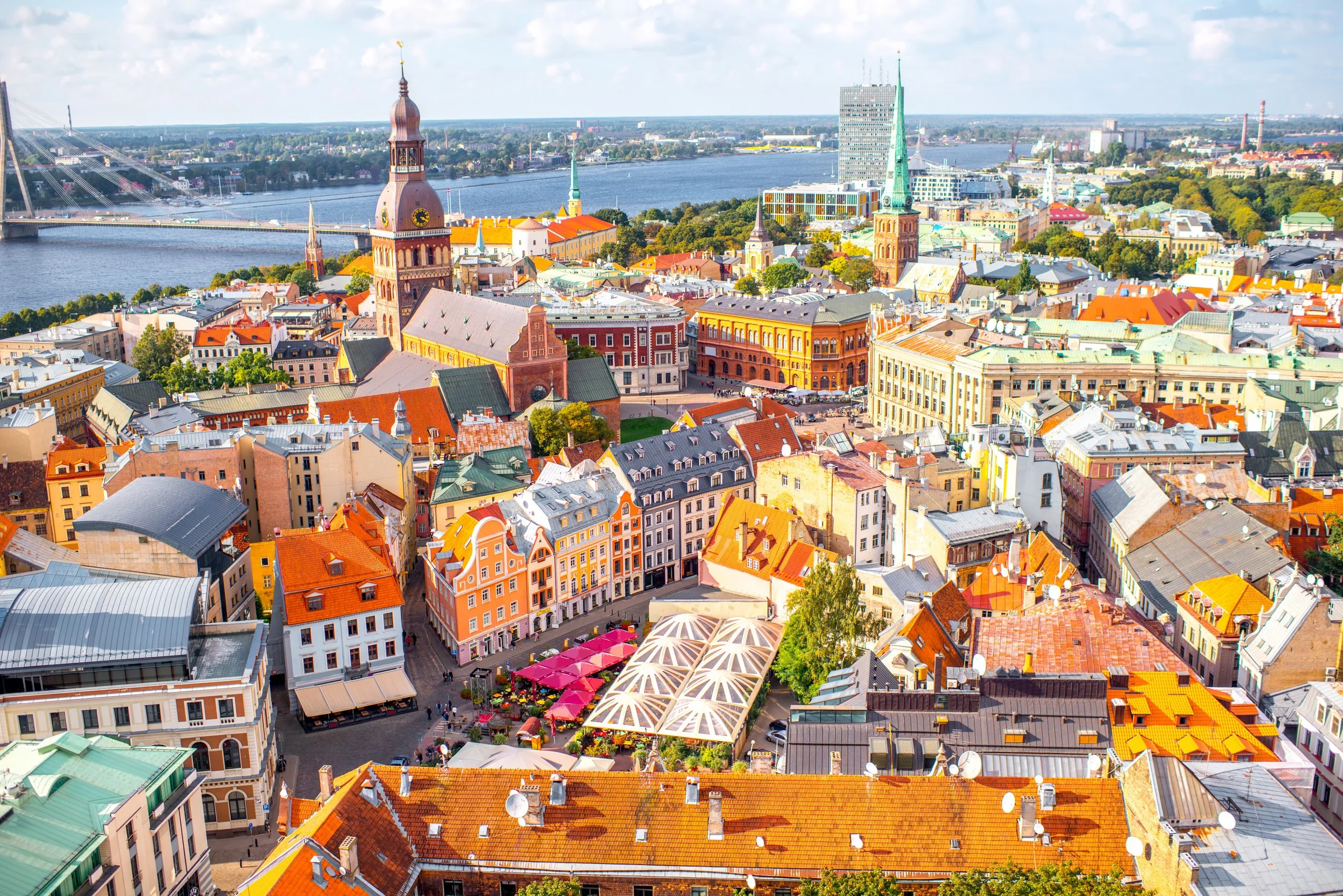 Vy över en stad vid vattnet med kyrktorn och moderna byggnader, klart väder.