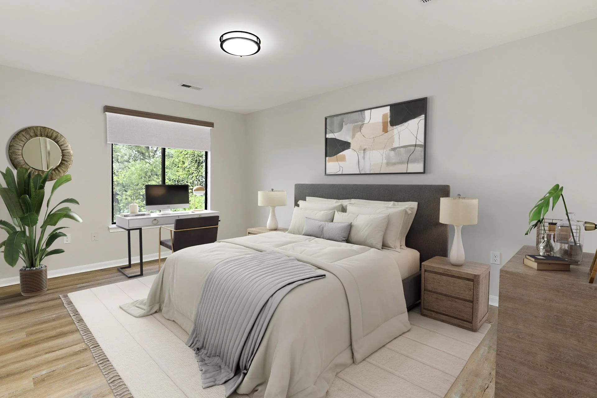 Modern bedroom with gray upholstered bed, white bedding, wooden nightstands with lamps, abstract artwork above bed, large window with greenery outside, potted plant, desk with computer near window, light-colored hardwood floors, and ceiling light fix