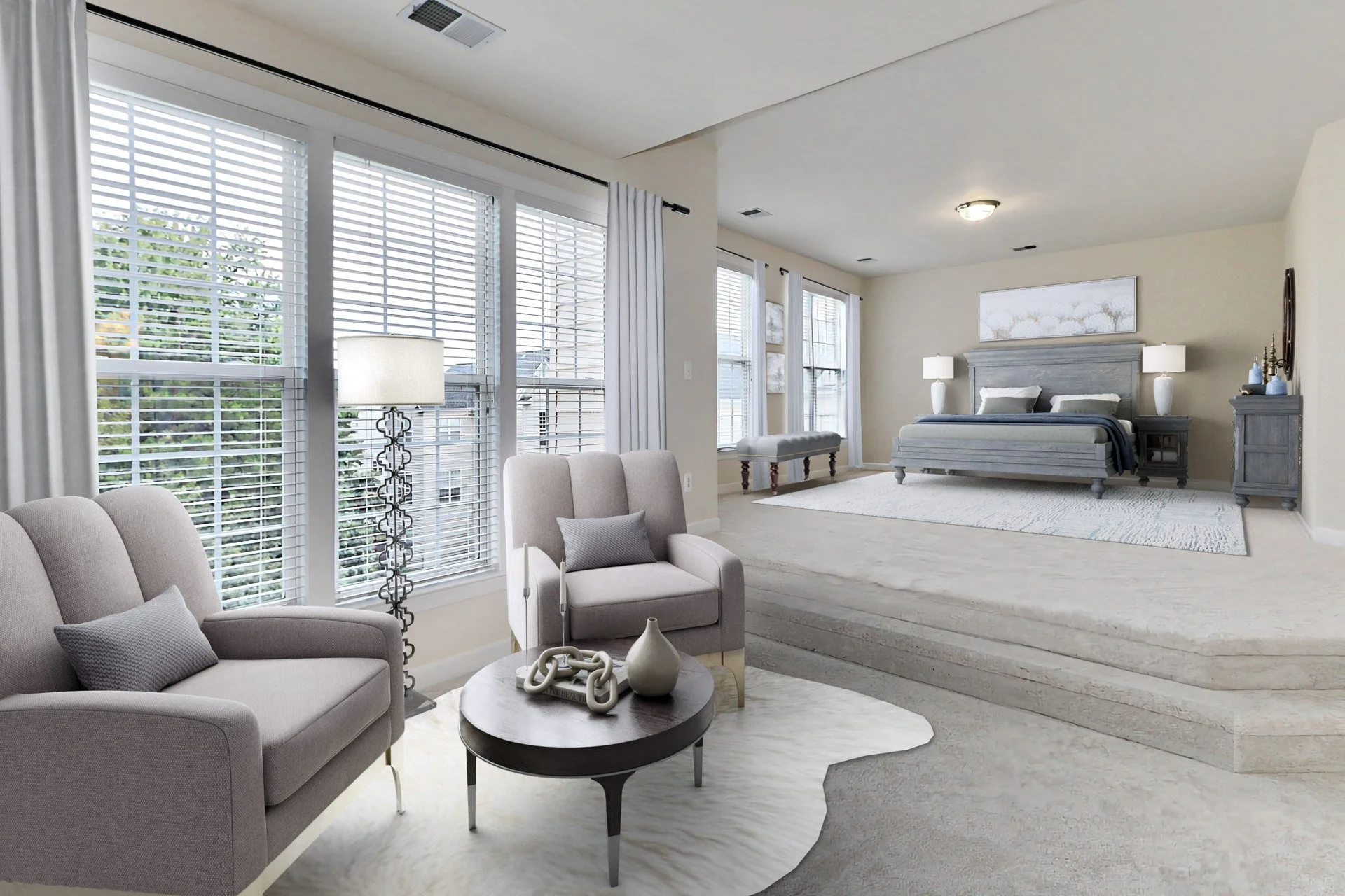 Living room with light-colored furniture, large windows with white blinds, a modern floor lamp, a beige armchair with a gray pillow, a small black coffee table with decorative items, and a raised bedroom area with a bed, nightstands with lamps, and w