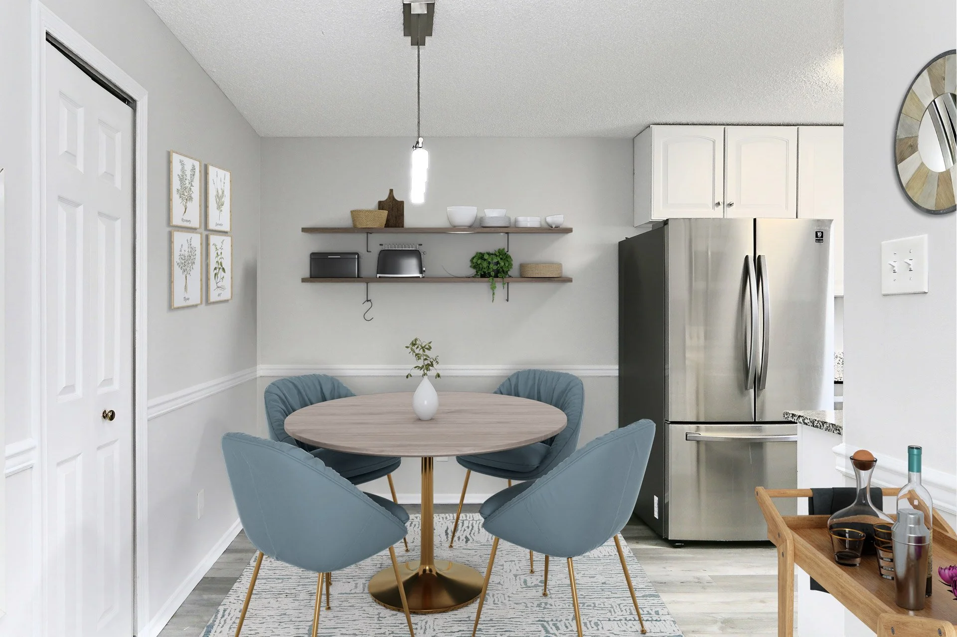 A modern dining area with a round wooden table, surrounded by five blue upholstered chairs, in a light gray kitchen. There are two floating shelves with decor and kitchen appliances, and a stainless steel refrigerator on the right.