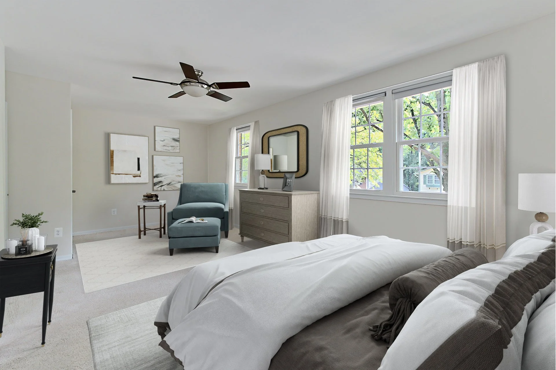 A spacious bedroom with a large bed, light-colored bedding, and a gray blanket. There's a bedside lamp, a dresser with a mirror, a blue armchair with an ottoman, and decorative artwork on the walls. The room has windows with white curtains, a ceiling