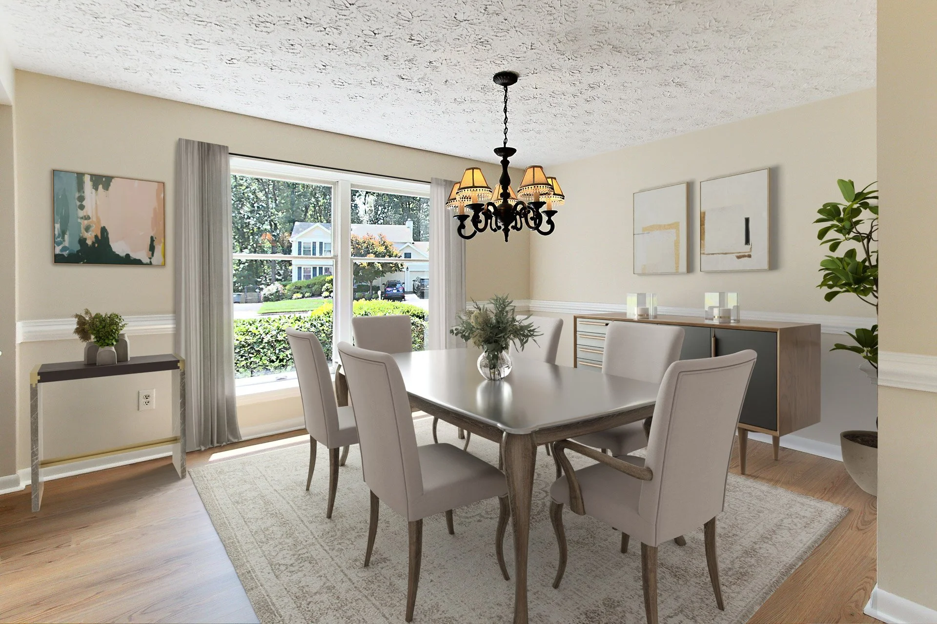 Dining room with a chandelier, six white upholstered chairs around a rectangular wooden table, a sideboard, a potted plant, large window with curtains, artwork on the walls, and a vase with greenery on the table.