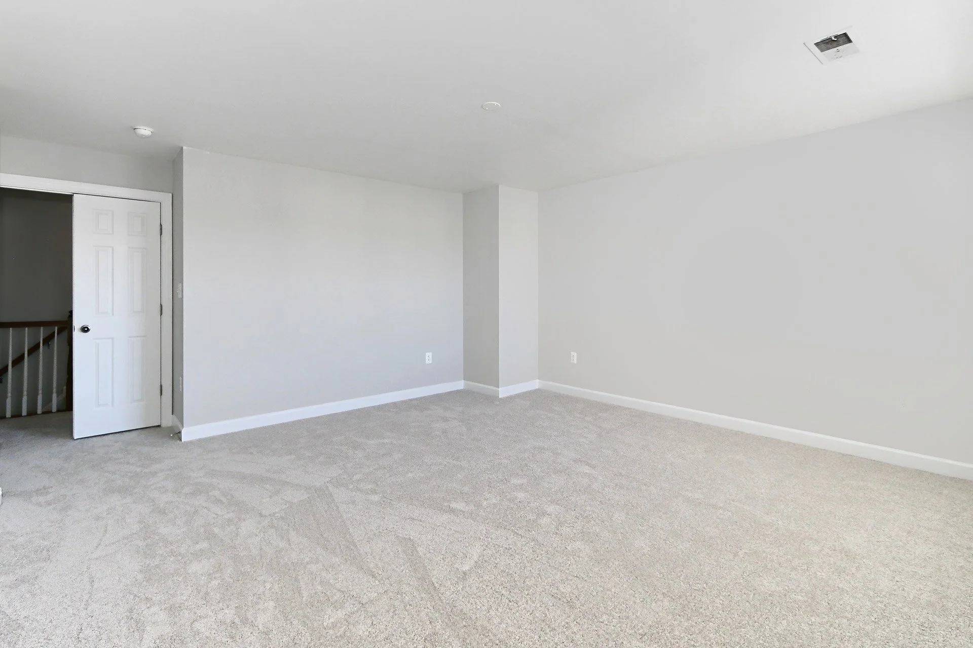 Empty room with white walls, beige carpet, white baseboards, a white door, and a ceiling vent.