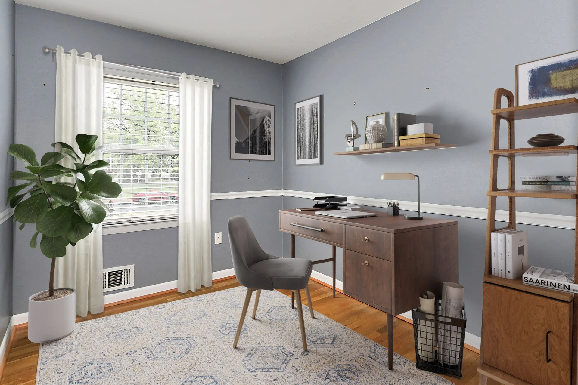 Home office with gray walls, wooden floor, window with white curtains, green potted plant, desk with chair, framed artwork on wall, bookshelf with decor, and a rug.