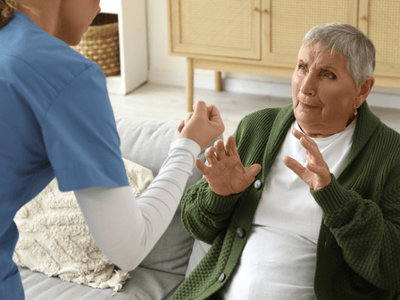 A nursing home worker clenching her fist and threatening a resident.