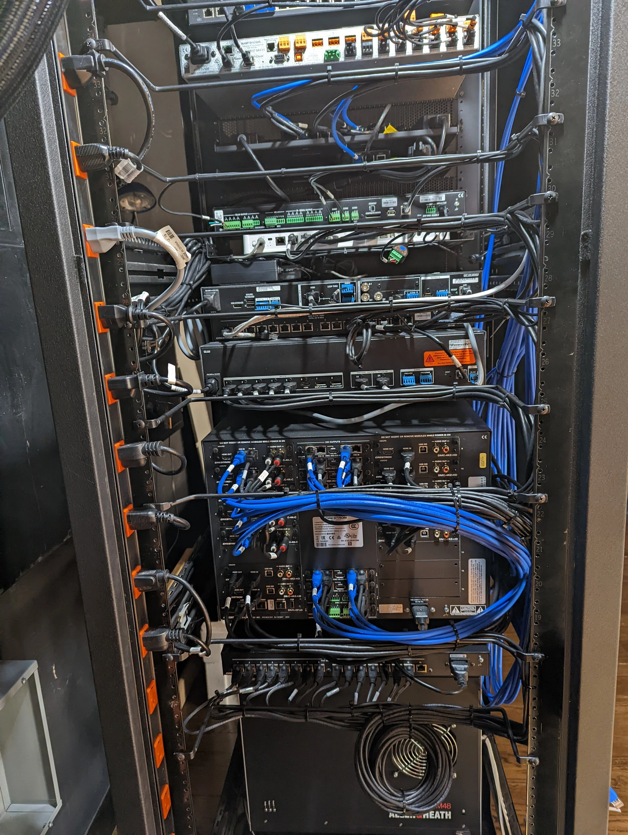 A server rack filled with networking and electronic equipment with black and blue cables connected to various devices.