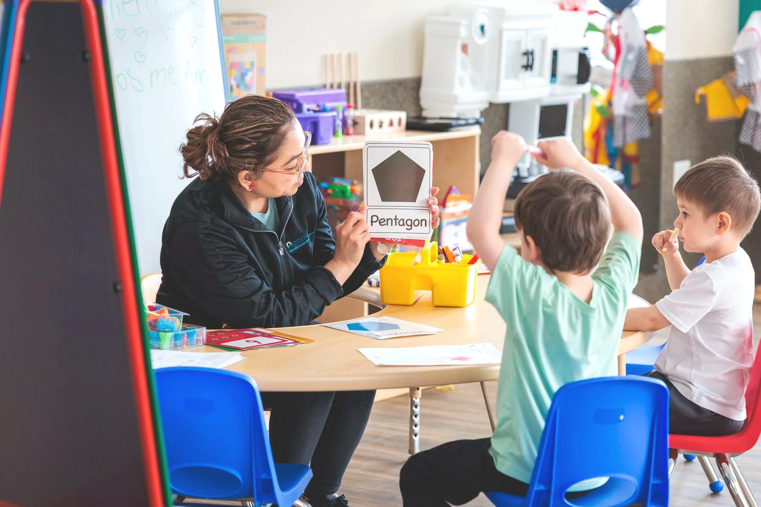 Child pouring colorful liquid from a blue bottle into a container, with other bottles of pink and yellow liquid nearby.