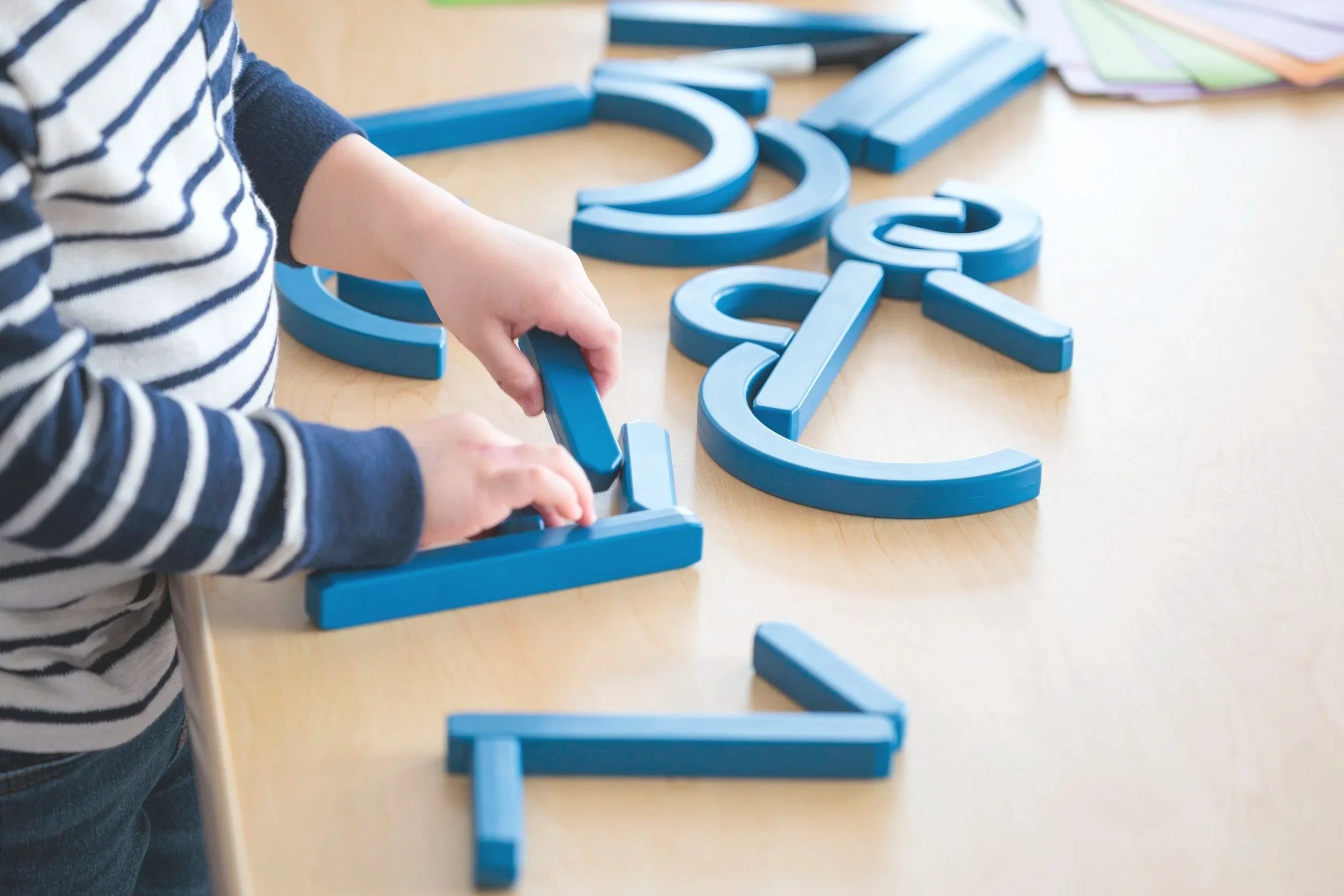 A young boy putting shapes together on a wooden table