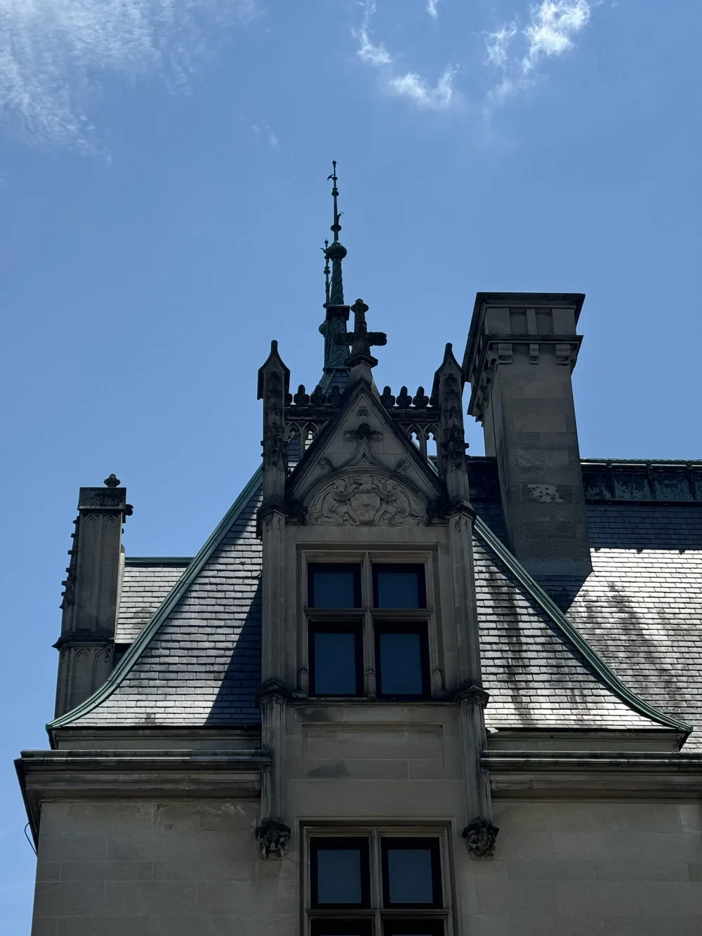 Person relaxing in black boots and jeans sitting by a fire pit at night with a red metal bench and apartment buildings in the background.