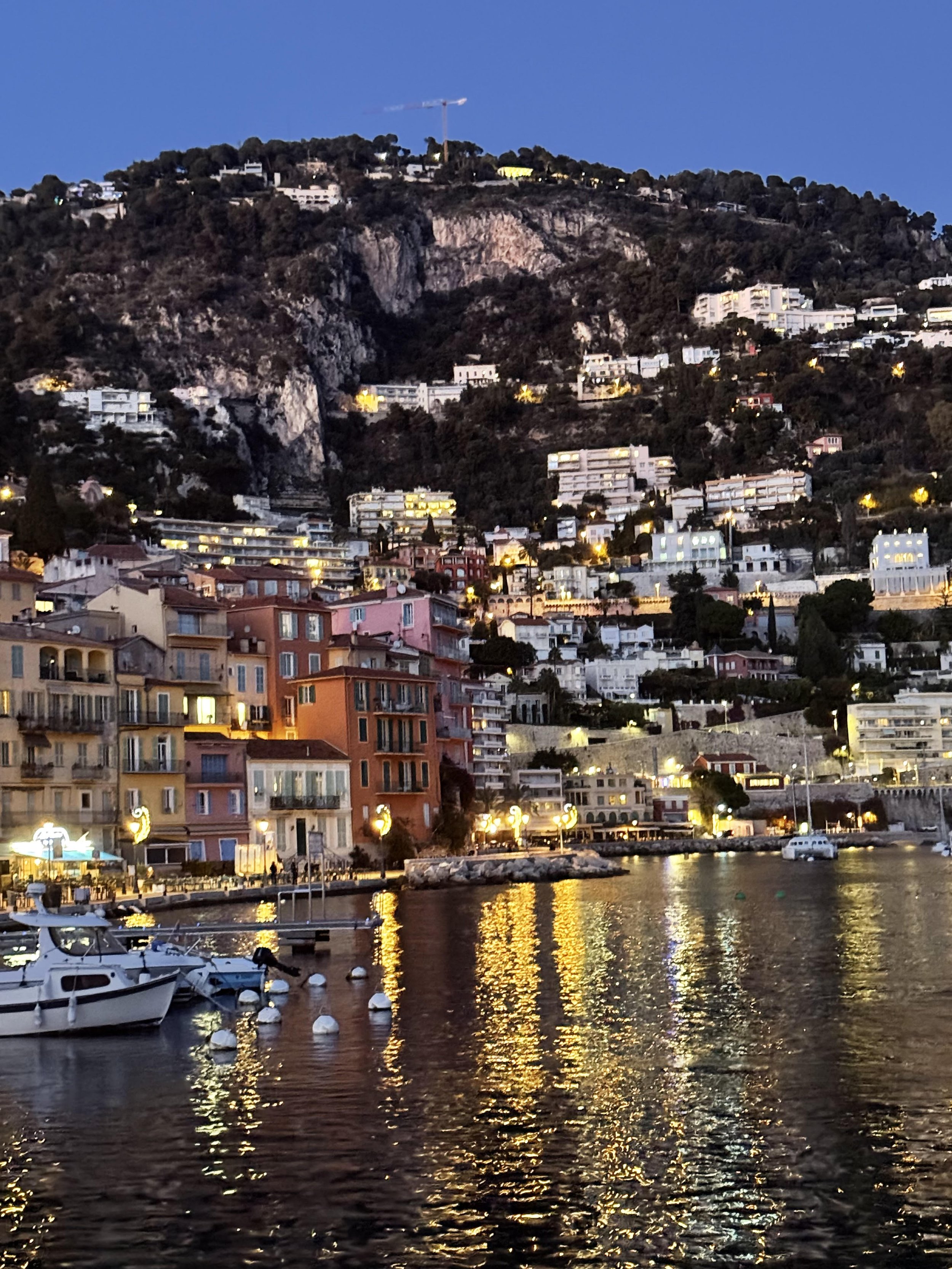 Abstract black sculpture with flowing, curvy shapes standing outdoors in a snowy landscape under a clear blue sky.