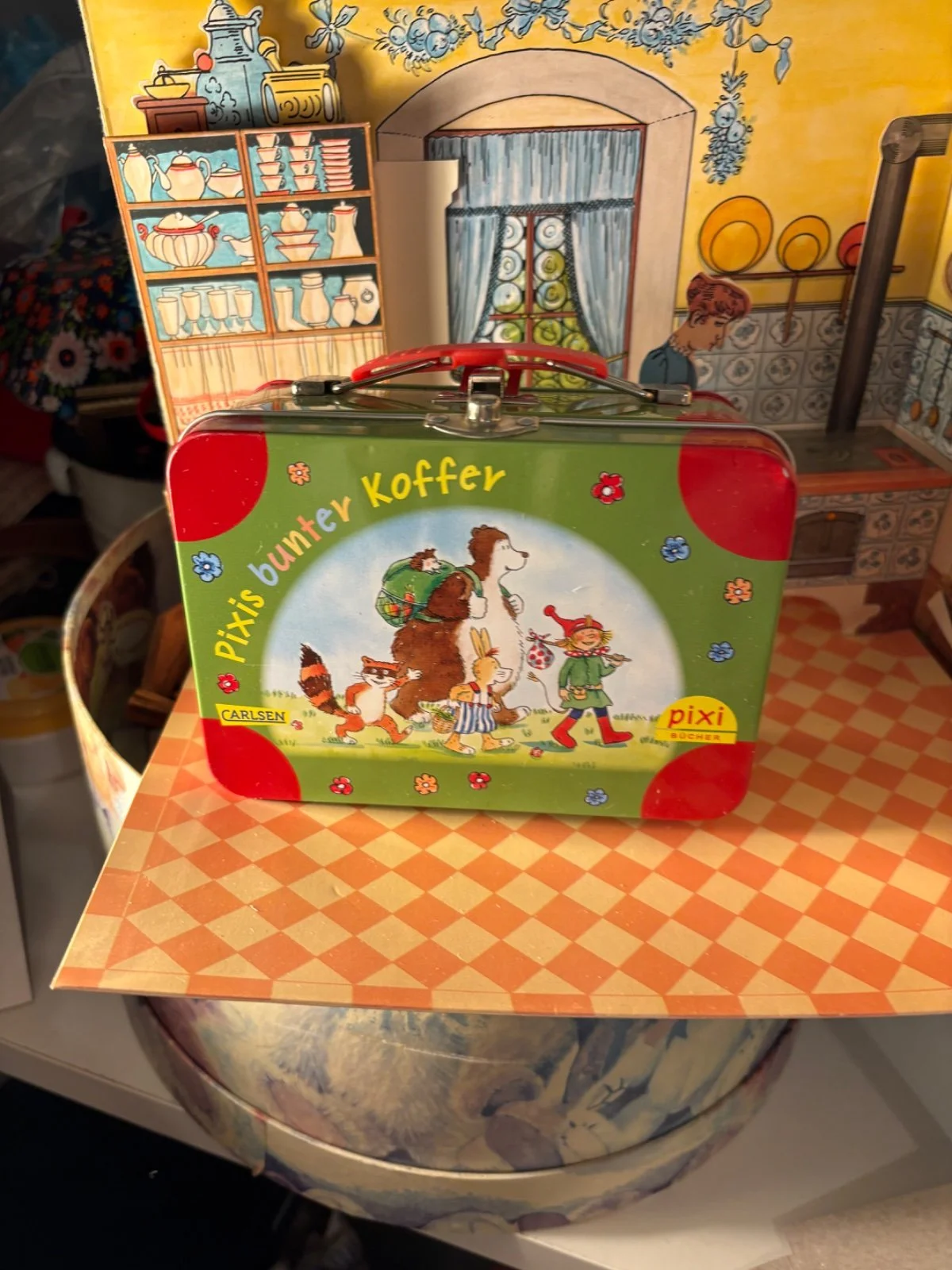 Kleiner grüner Blechkoffer mit bunter Tierillustration und rotem Griff
