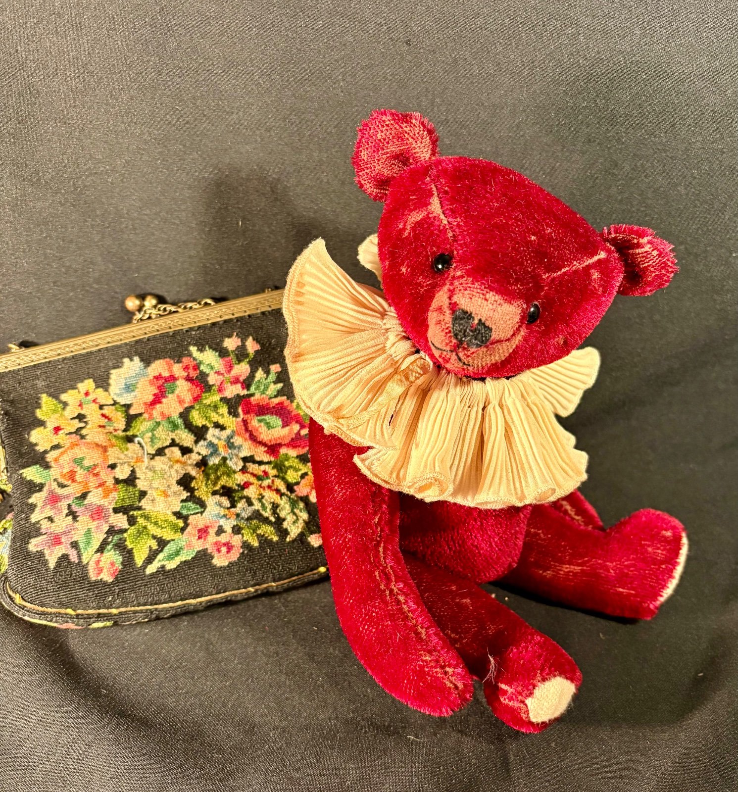 Teddybär im Sitzen neben Tapisserie-Tasche, Frontalansicht mit Rüschenkragen