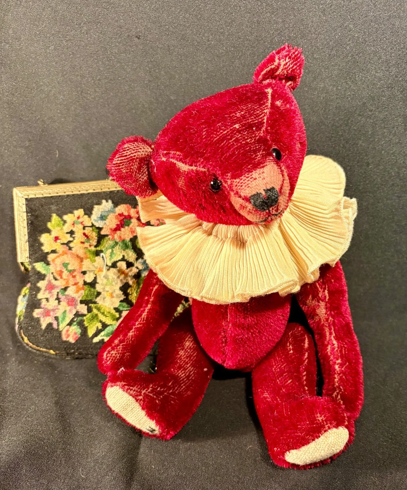 Teddybär von oben fotografiert, Rüschenkragen und helle Fußsohlen sichtbar