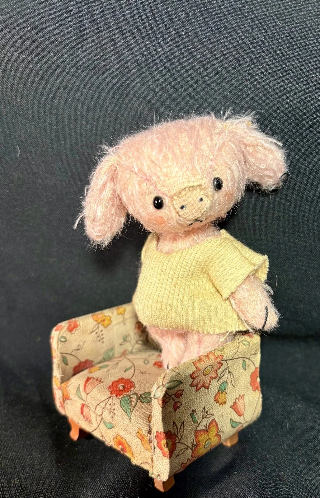 Schweinchen steht im Sessel, Seitenansicht mit gelbem Shirt