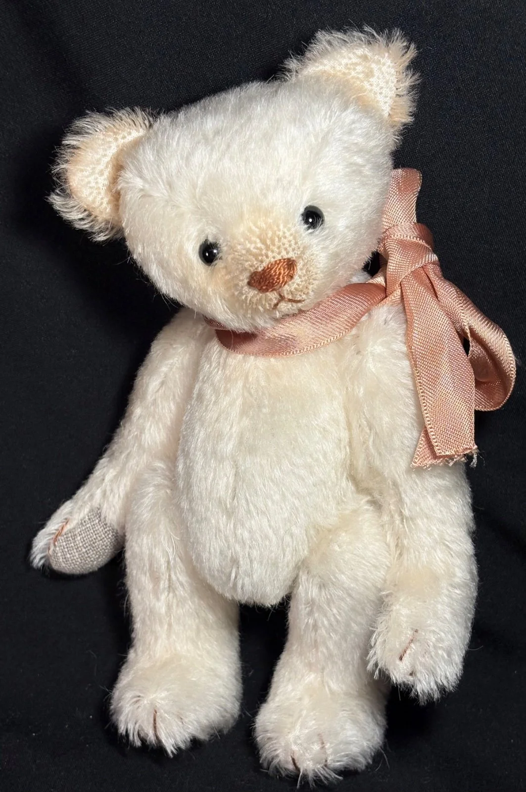 Cremeweißer Teddybär stehend von vorn, mit rosafarbener Satinschleife um den Hals