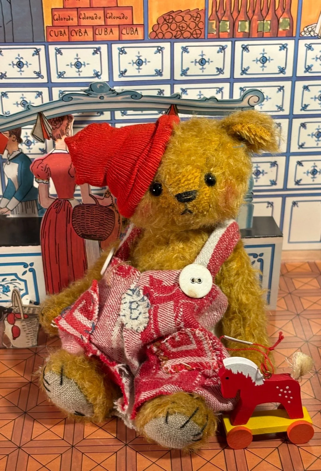 Teddybär Pelle von vorn sitzend mit rotem Holzpferd auf Rädern