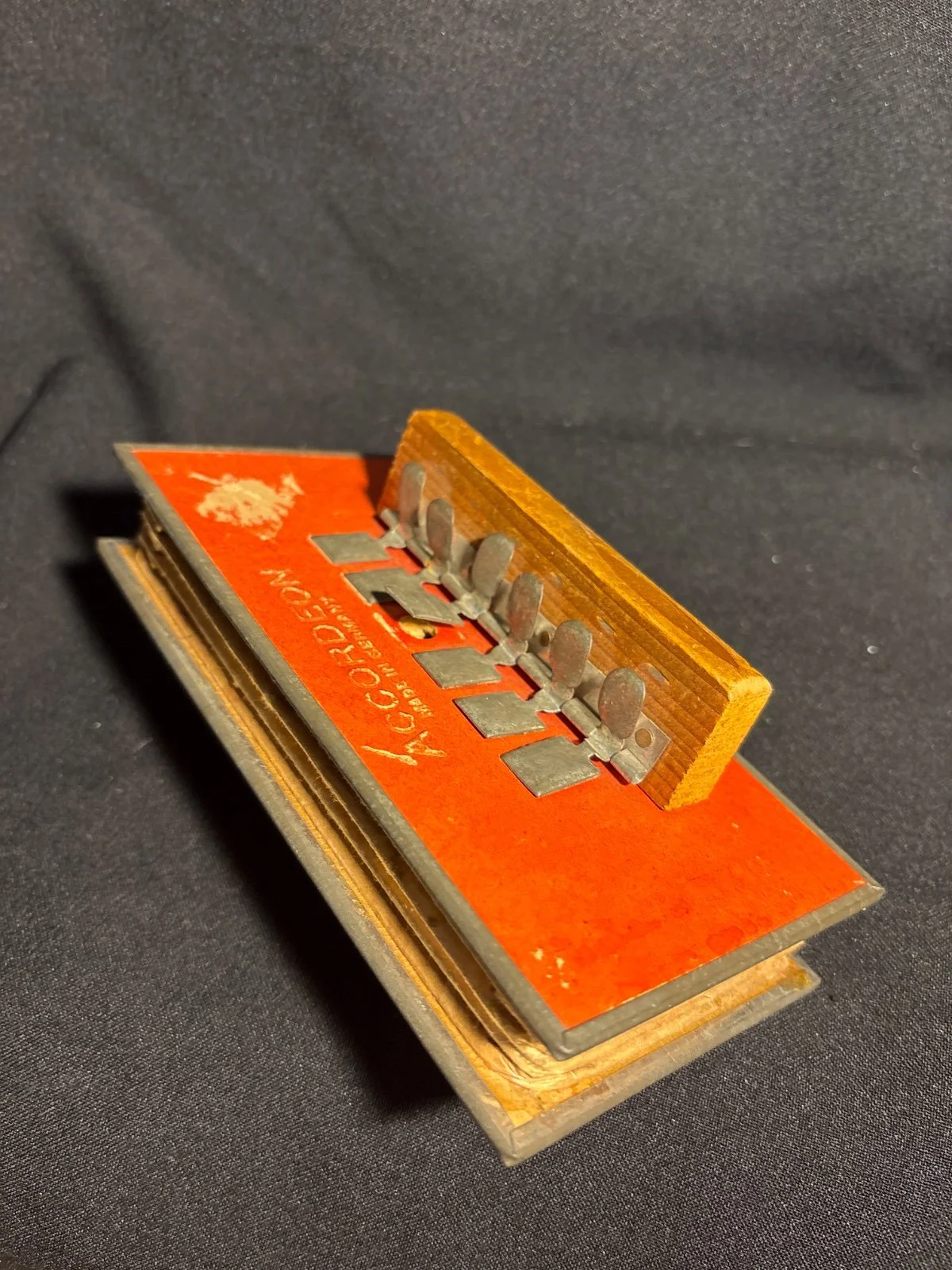 Kleines rot-oranges Spielzeug-Akkordeon mit Metalltasten und Schriftzug 'Accordeon Made in Germany'