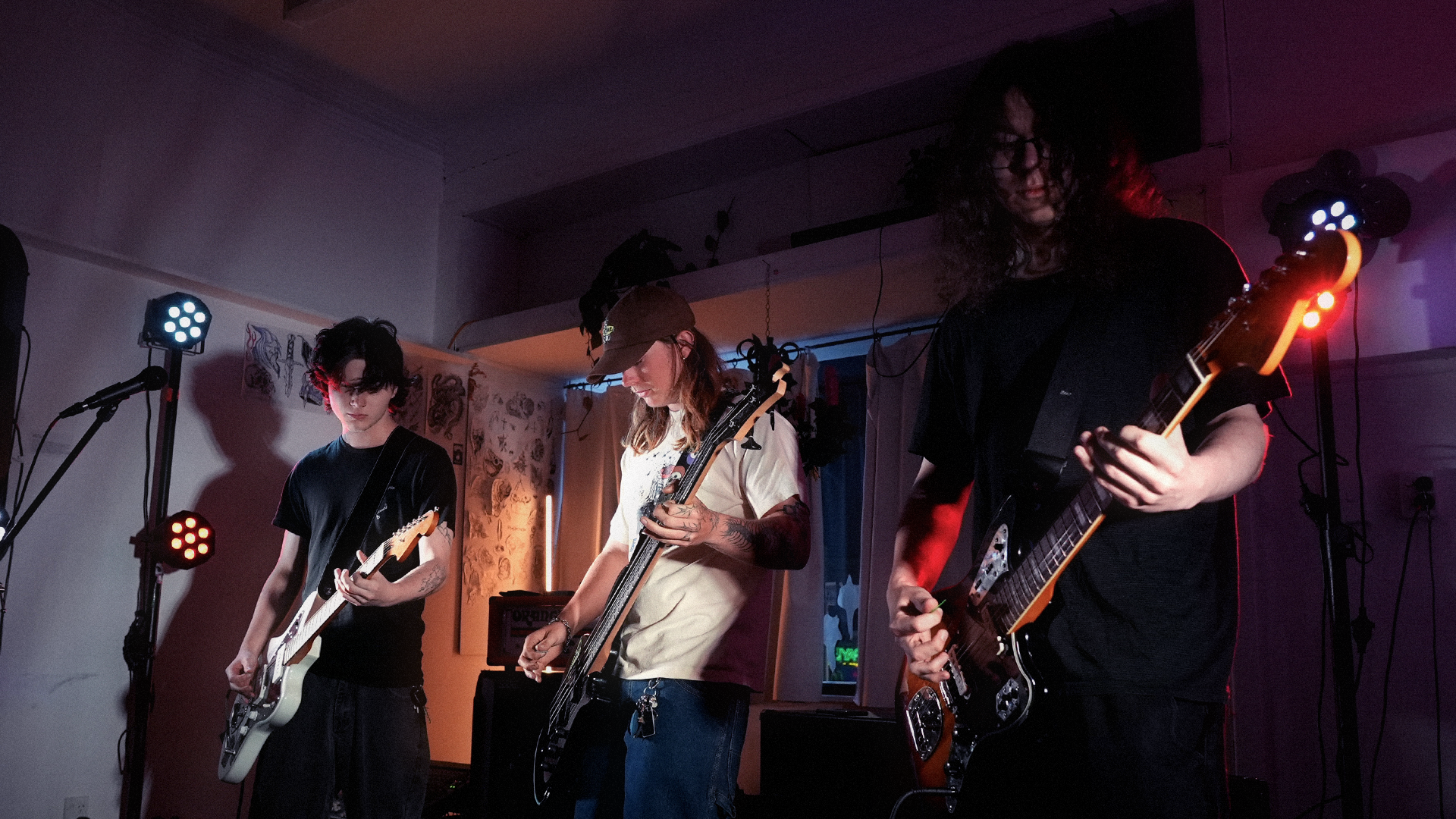 Three young musicians playing electric guitars on a dimly lit stage during a live performance.
