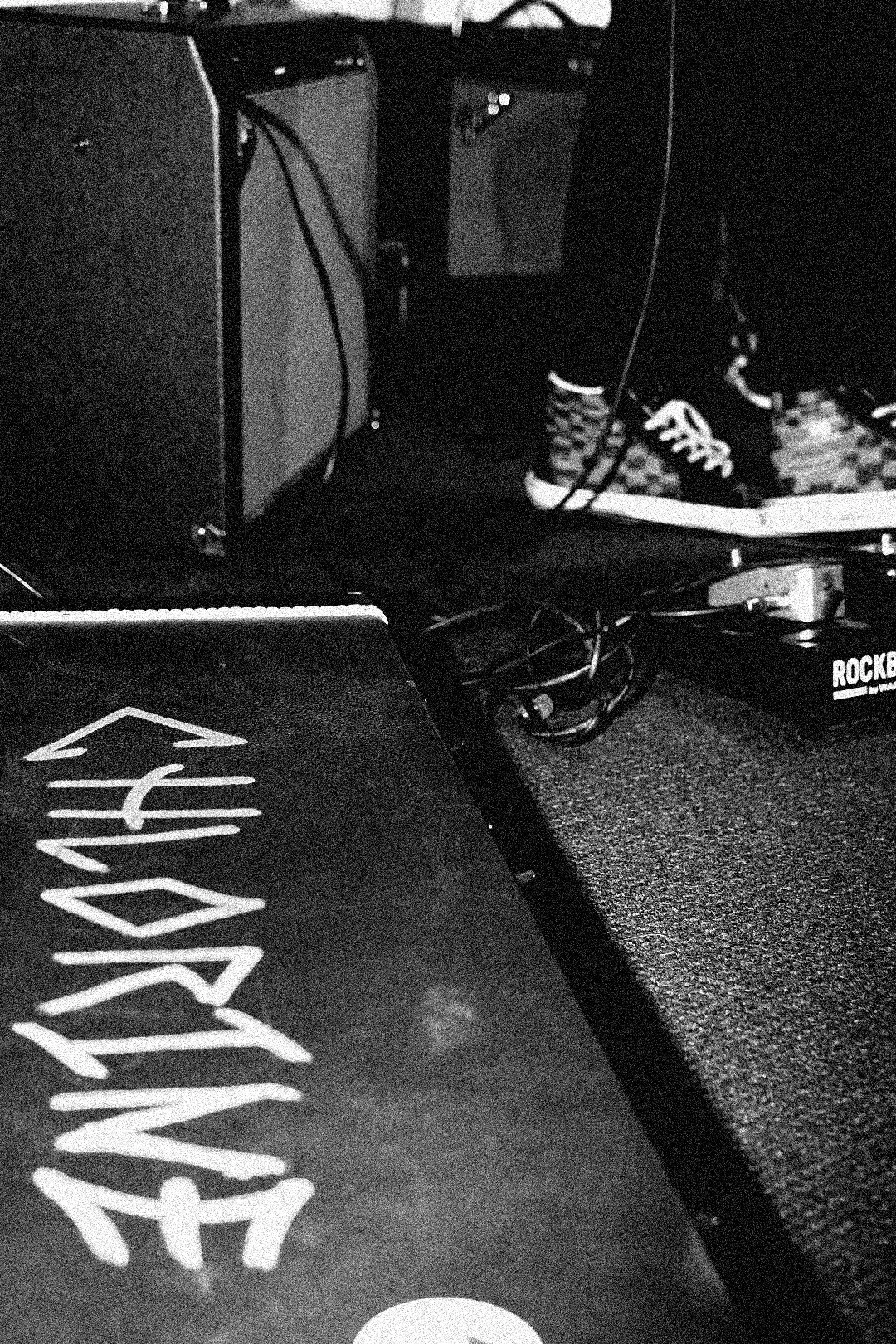 Black and white image of a table with painted words, some electronic equipment, and cables on a textured surface.