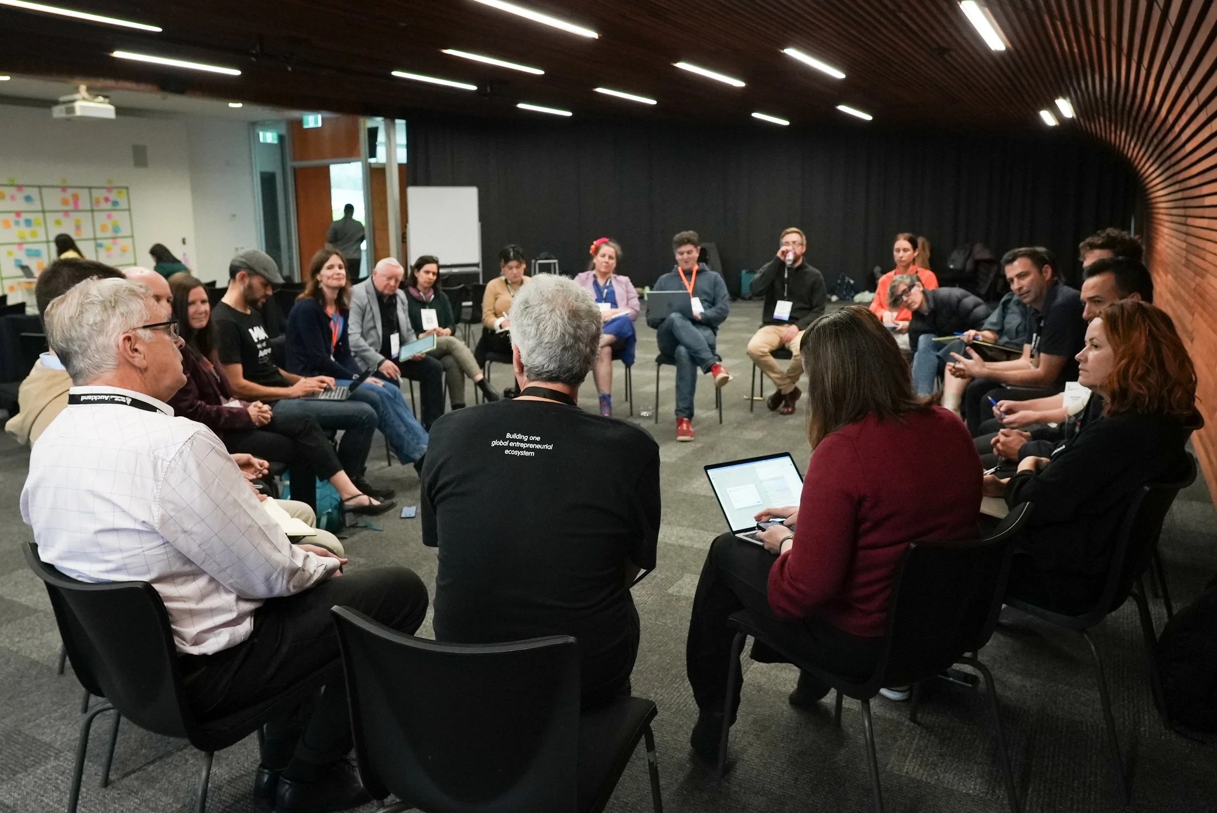Group of people sitting in a circle in a conference room, participating in a discussion or workshop.