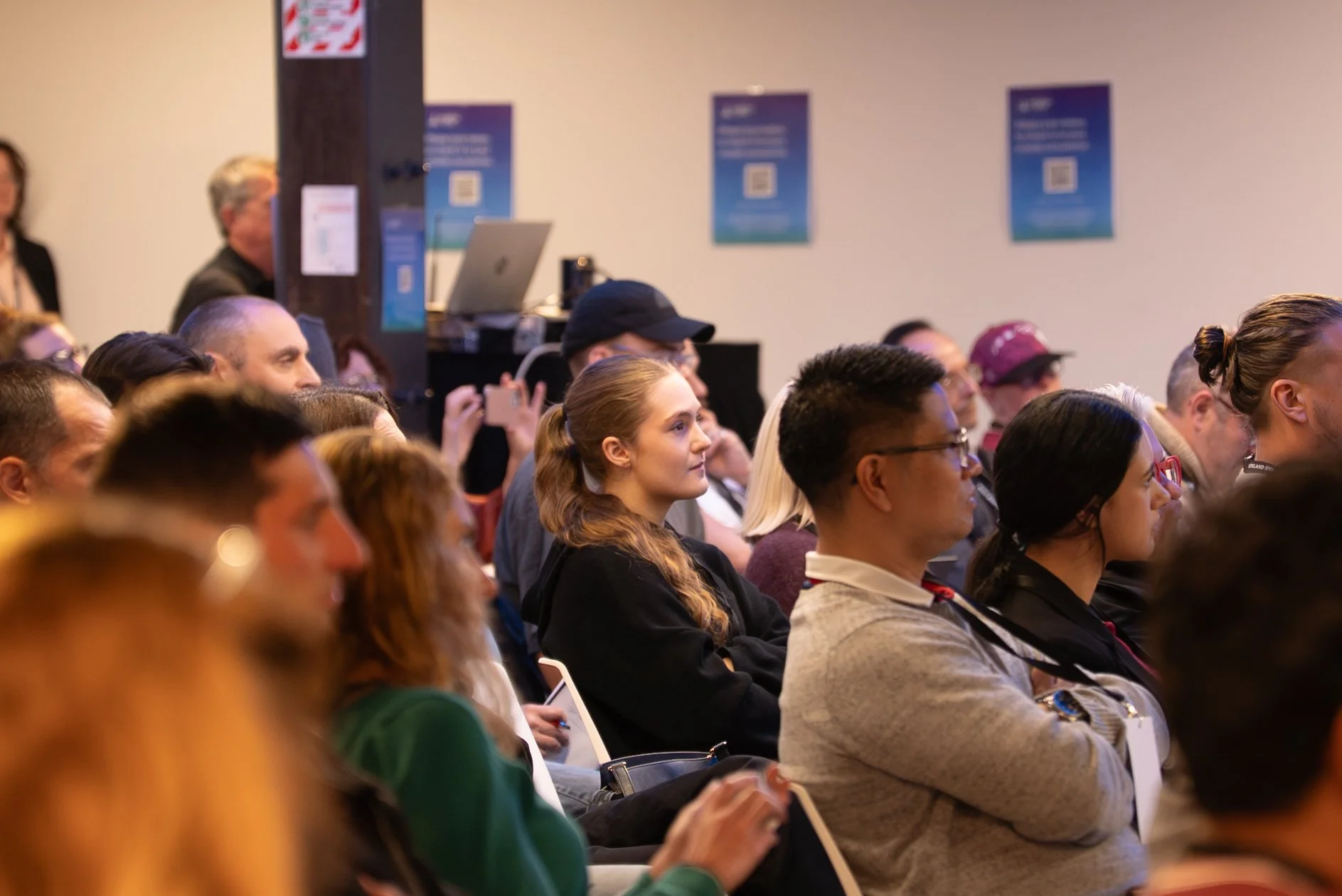 Audience members attending a conference or seminar, sitting and listening attentively in a room.