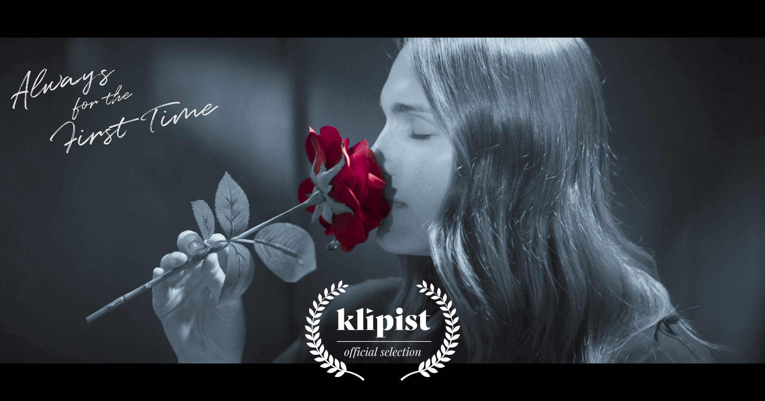 A woman with long hair closes her eyes and holds a red rose near her face, with a black and white filter except for the red rose.