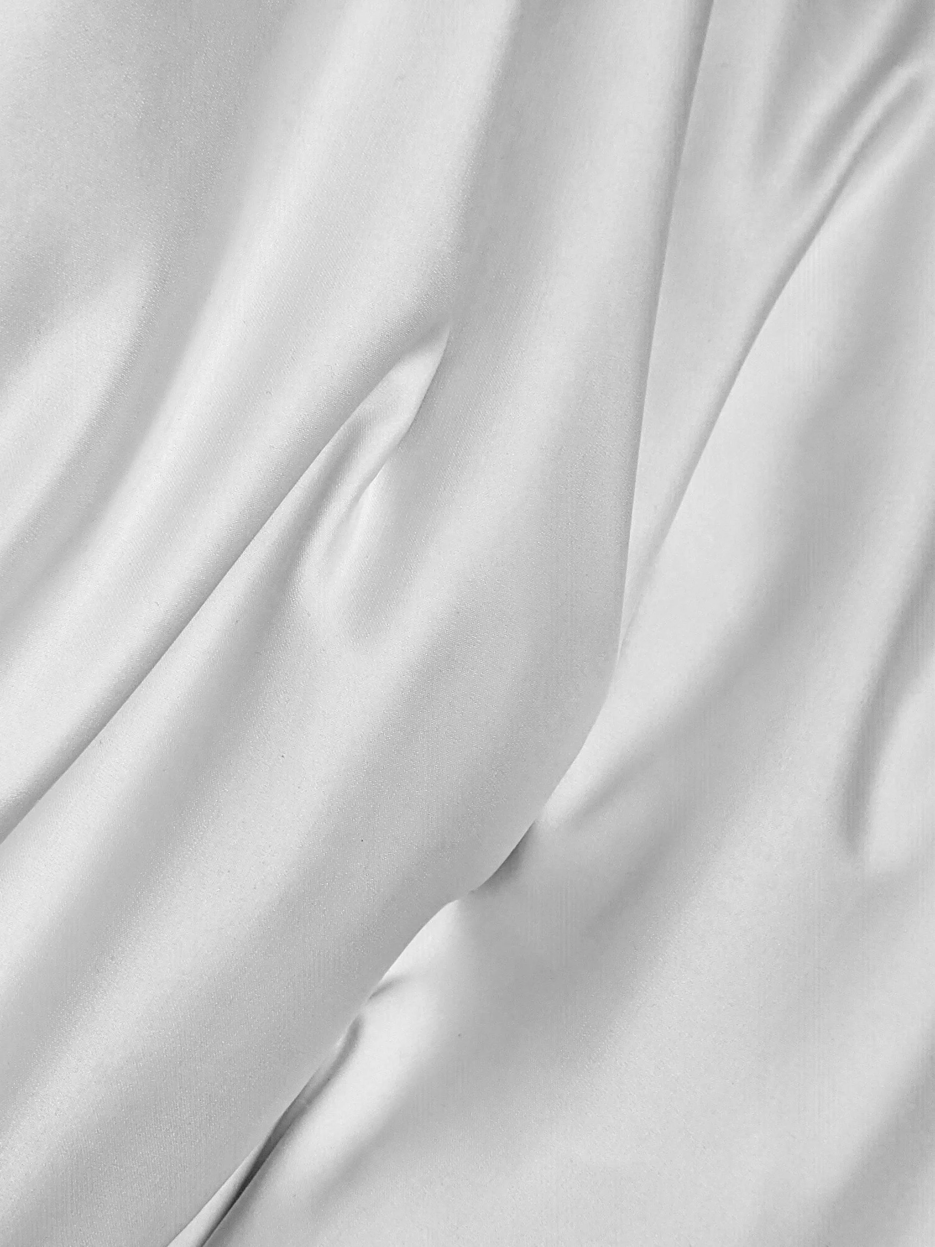 Close-up of smooth, white satin fabric with gentle folds and sheen.
