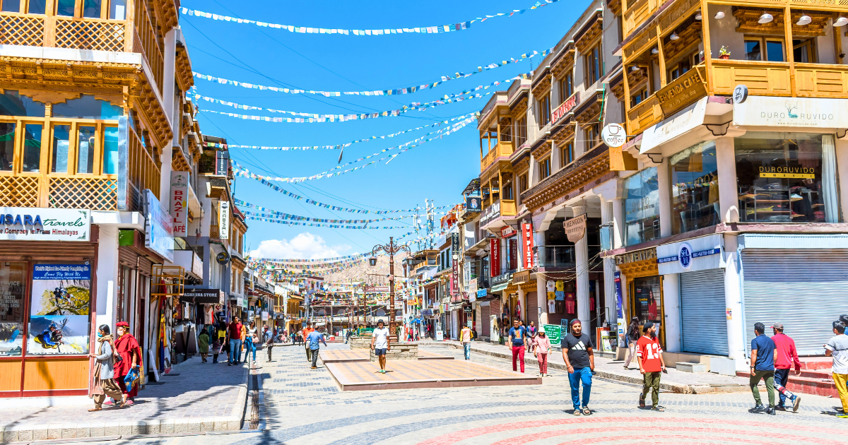 Leh Main Bazaar street with pashmina store sign and fewer people in the mid-morning