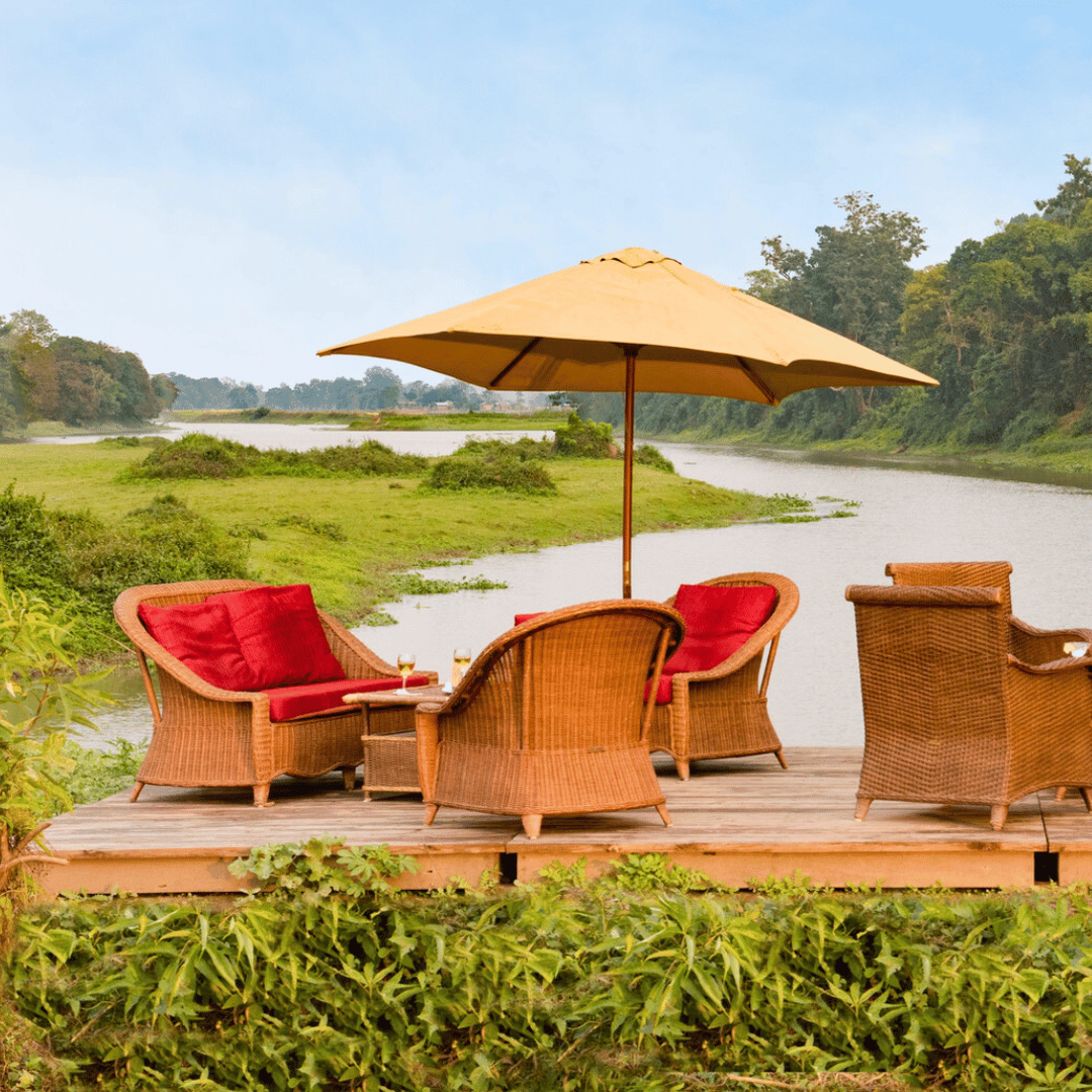 Outdoor patio with wicker furniture and a large umbrella overlooking a river and greenery