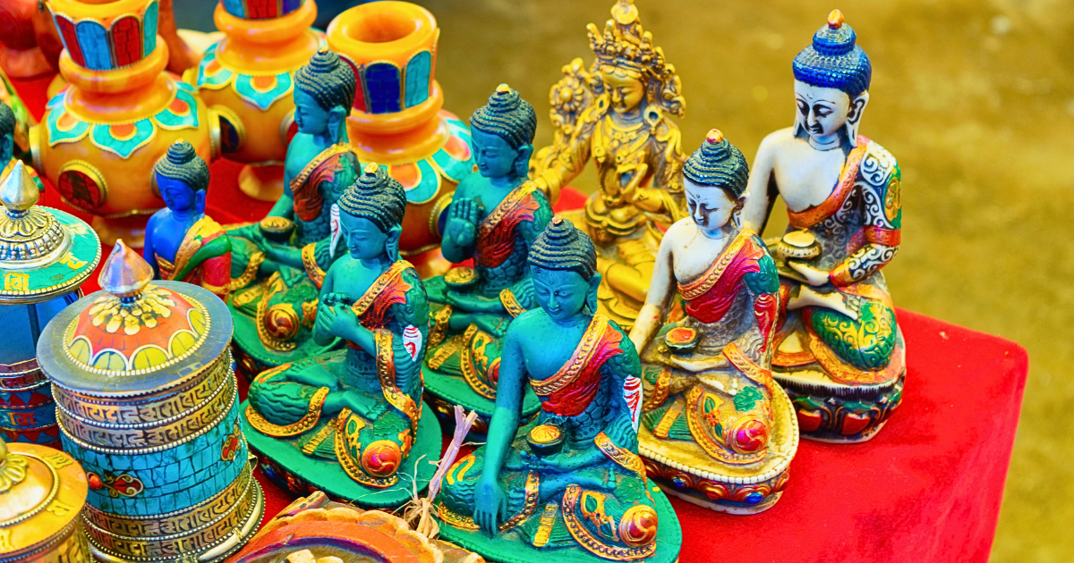 Painted Buddha statues, prayer wheels and turquoise-inlaid vases on a market stall in Leh