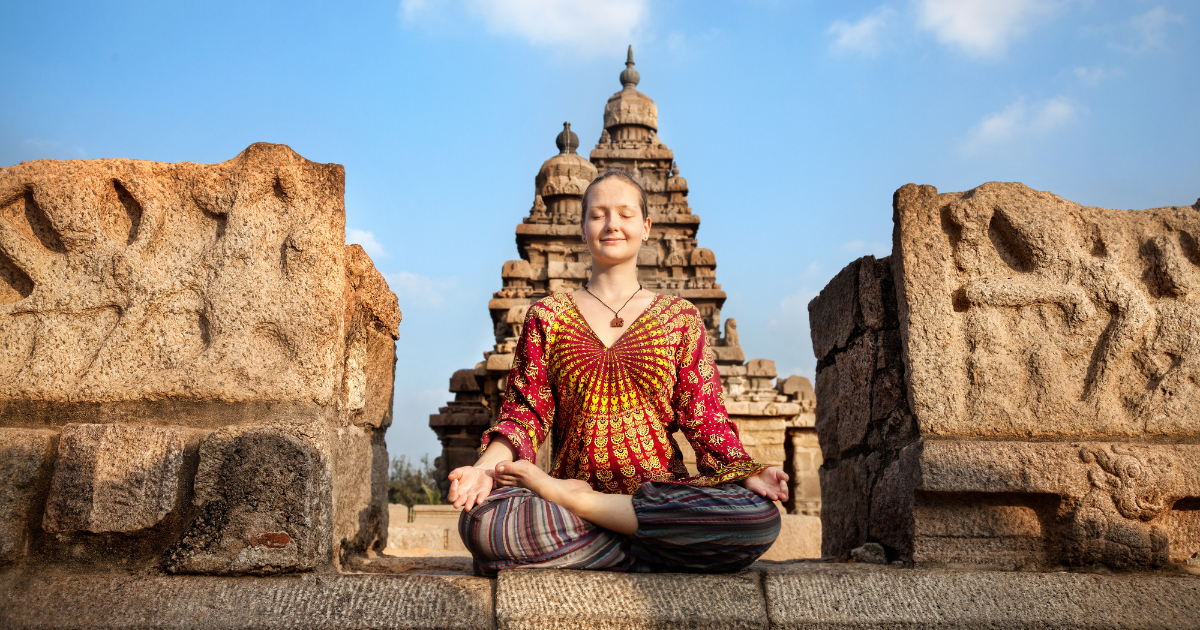 Traveller meditating in a cross-legged pose at the Shore Temple complex in Mahabalipuram Tamil Nadu