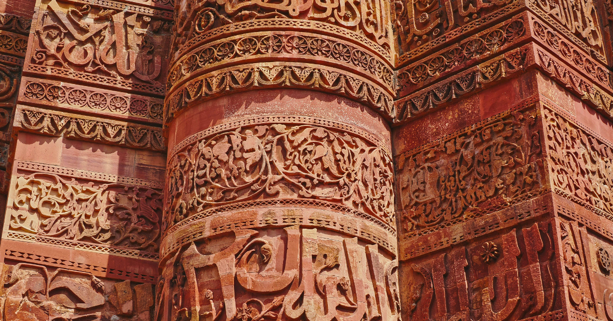 Close view of carved inscriptions and decorative bands on the red sandstone surface of Qutab Minar