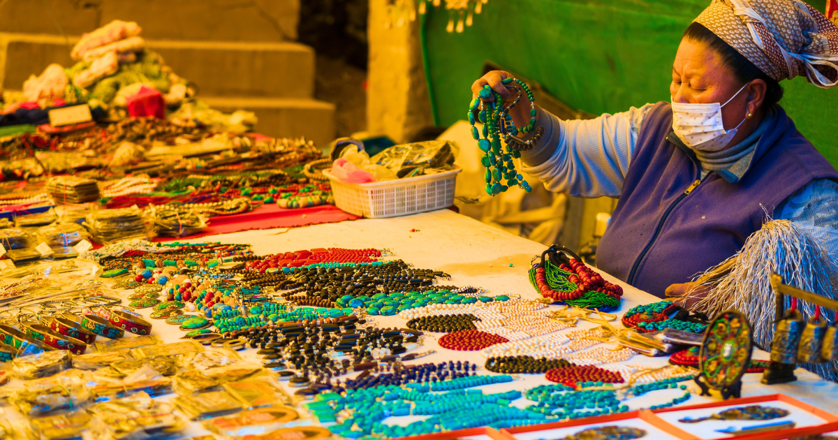 Tibetan stallholder at Moti Market in Leh holding up a strand of turquoise beads