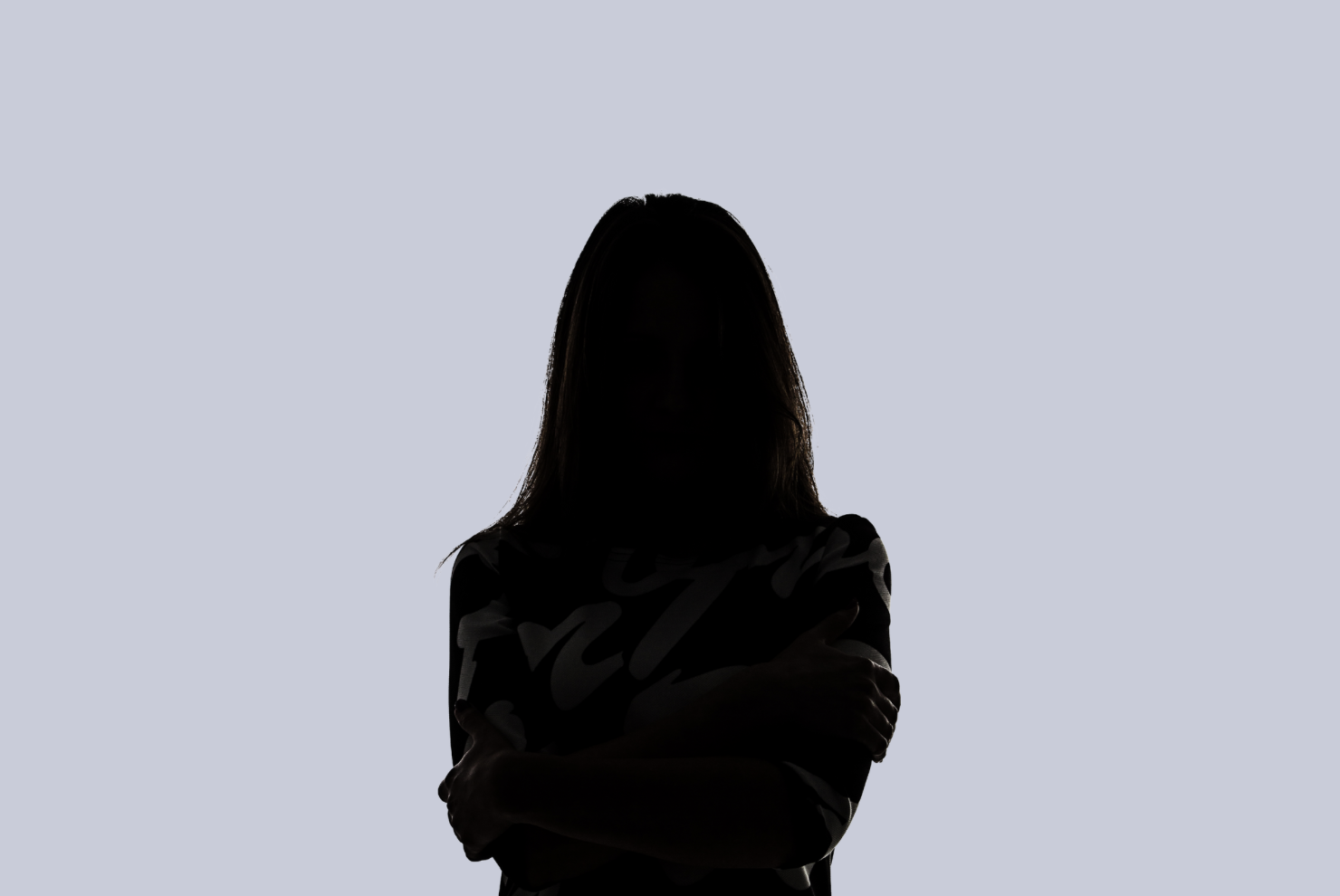 Silhouette d'une femme avec les bras croisés, fond gris clair.