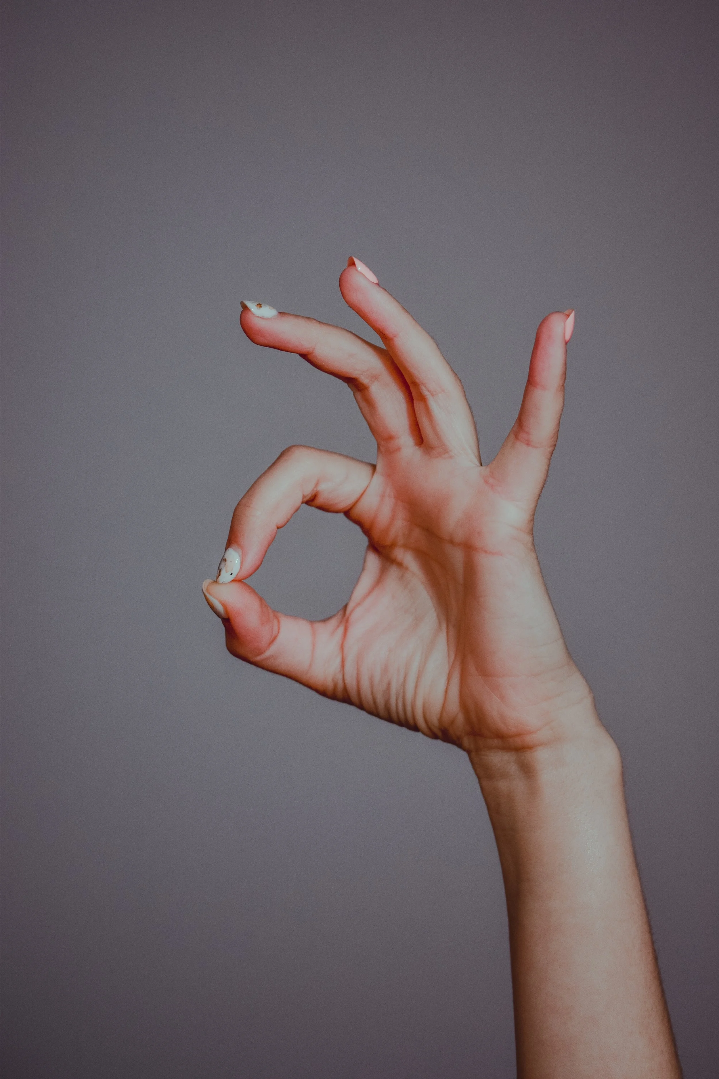 Une main faisant le signe du 'ok' avec un fond gris.