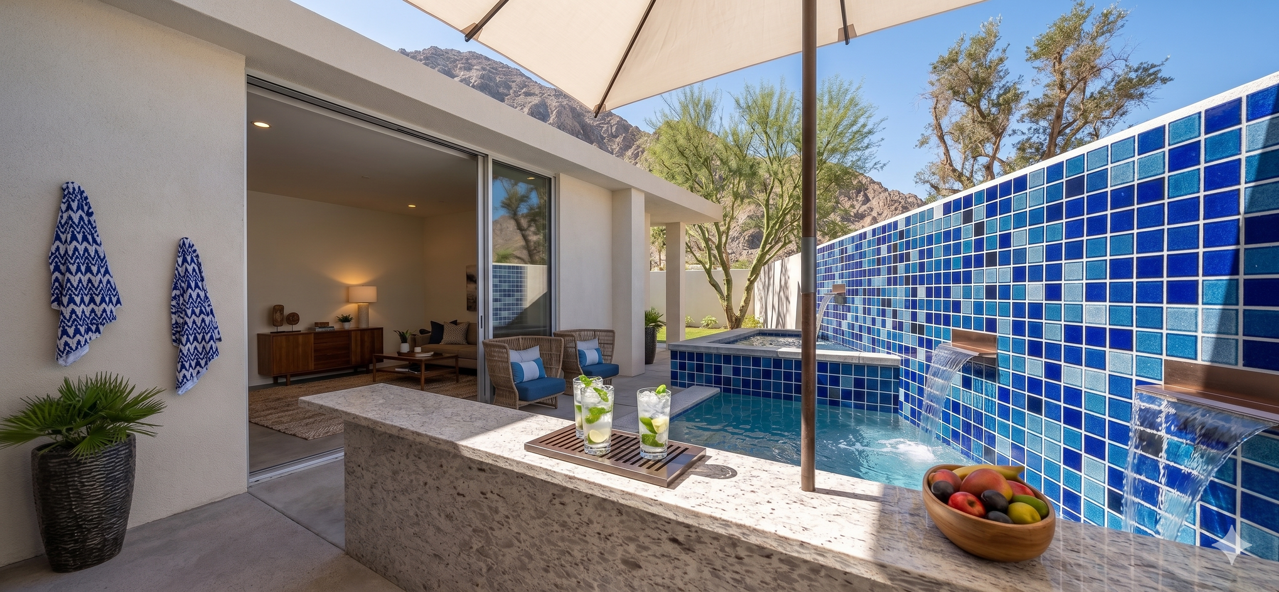 Outdoor patio area with a blue-tiled water feature, sitting area, and mountain views.