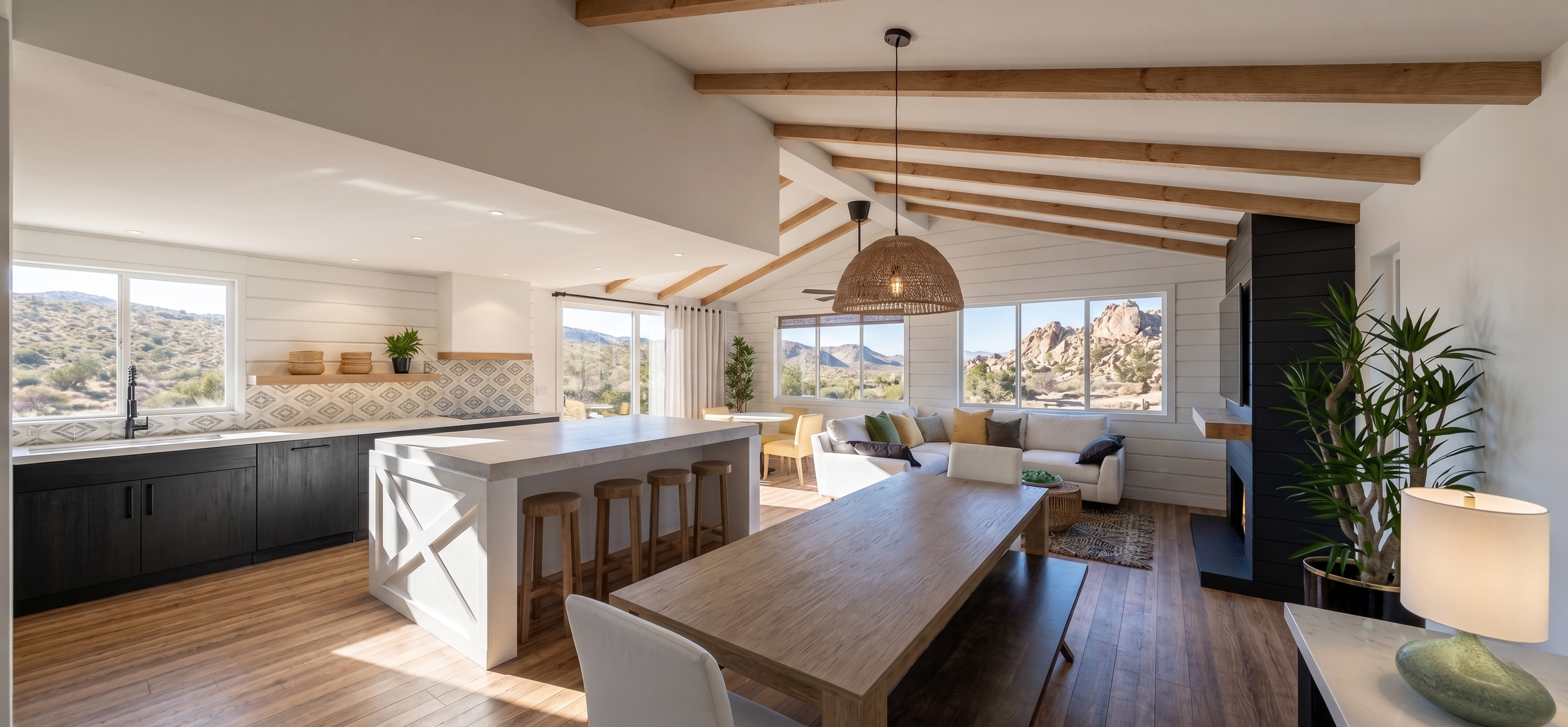 Bright open-concept living room with kitchen and dining area, featuring large windows with mountain views, wood beam ceiling, white walls, a black fireplace, green plants, and modern furniture.