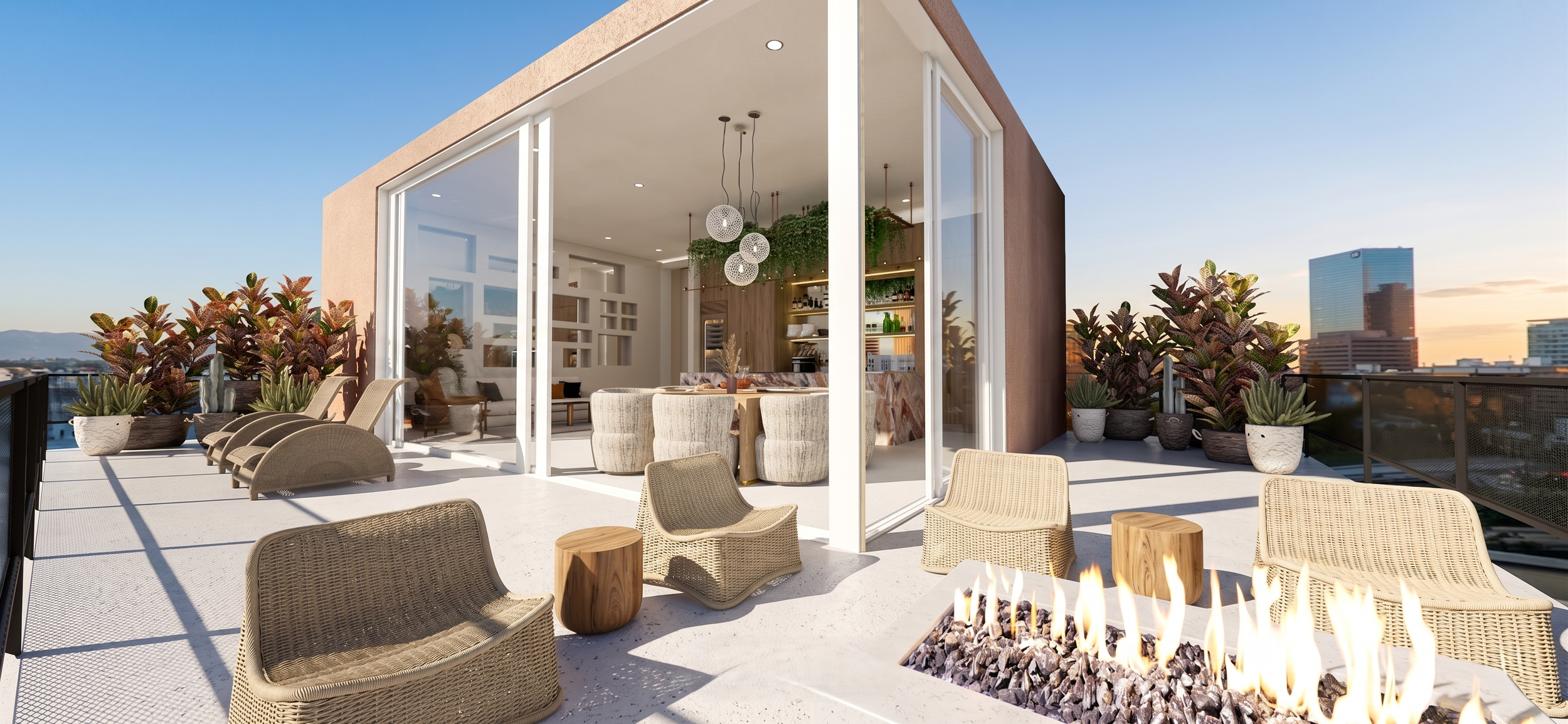 Modern rooftop terrace with lounge chairs, potted plants, a seating area, and a fire pit, overlooking a city skyline at sunset.