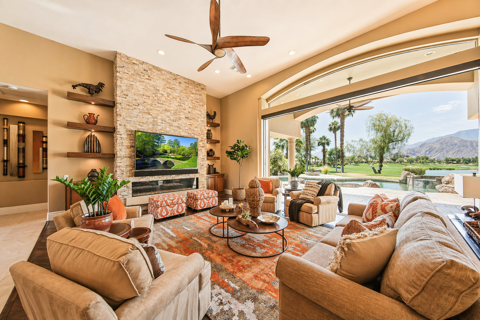 Living room with beige sofas, patterned pillows, a fireplace, a large window with a view of a golf course and mountains, and decorative items on shelves.