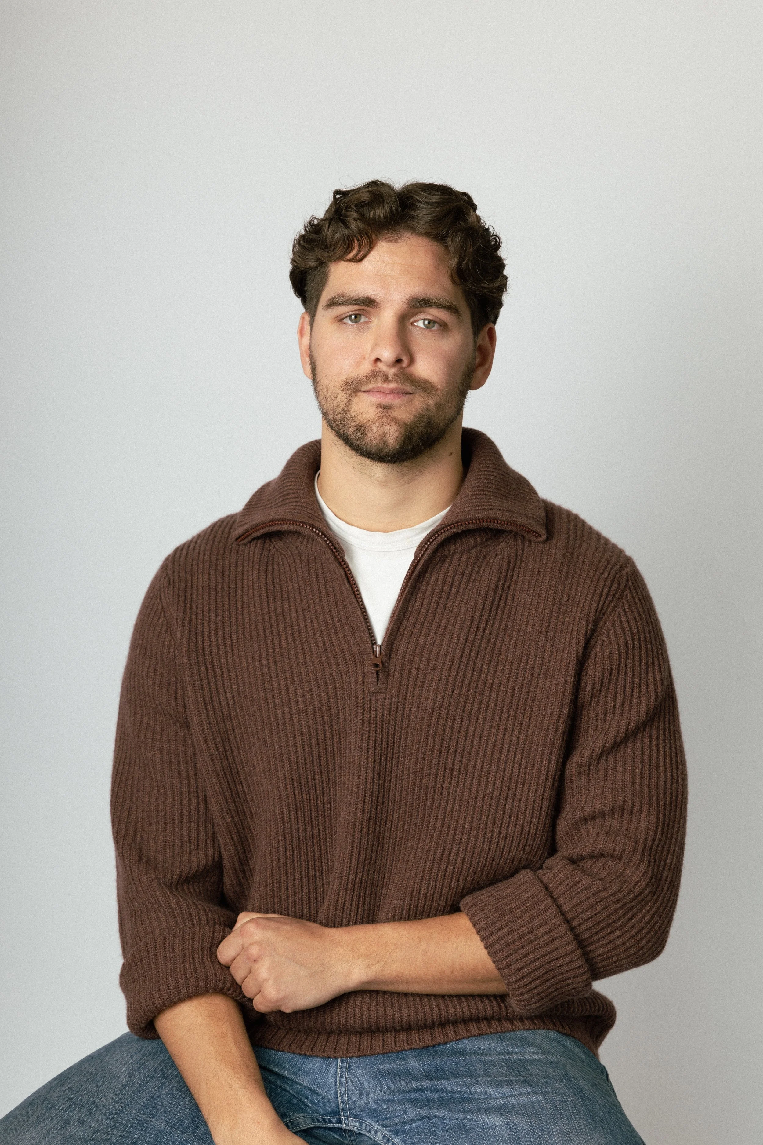 oscar revelins author headshot sitting in a brown knit sweater