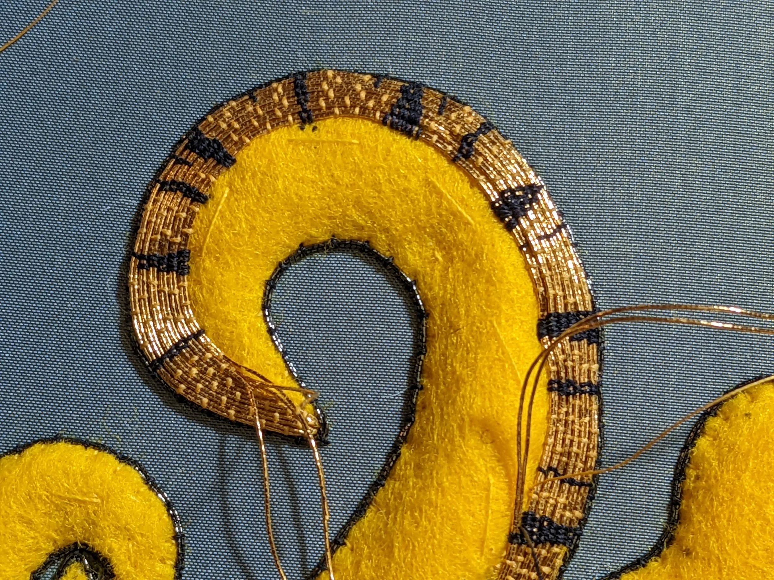 Stitching gold thread down with black silk to make stripes (and yellow silk to blend in).
