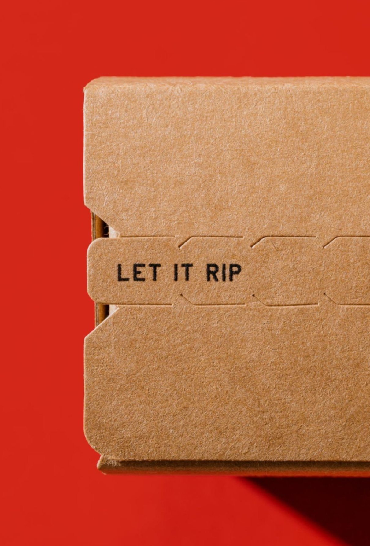 Close-up of a cardboard box with a tab that reads "LET IT RIP" against a red background.