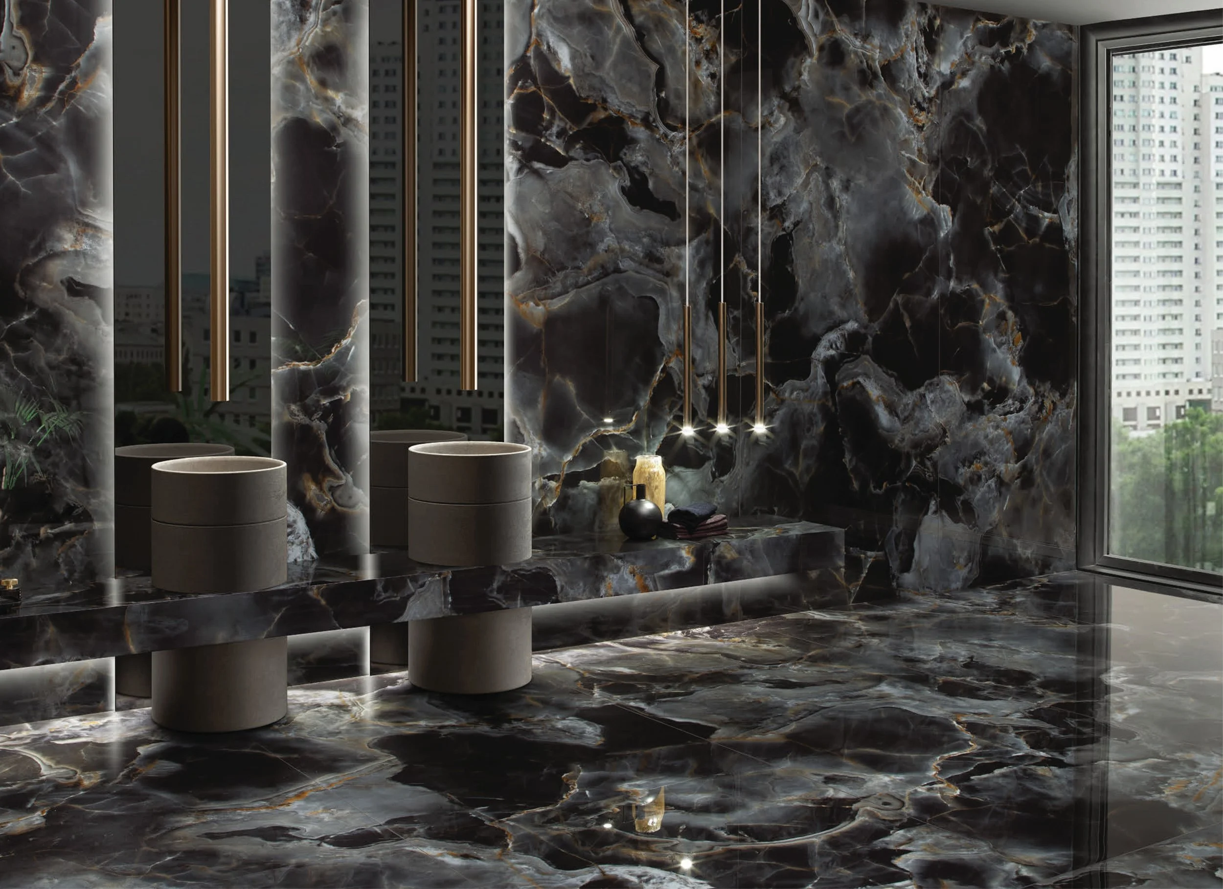 Modern bathroom with black and gold marble walls and floors, a large window with city view, two concrete sinks, and decorative lighting.