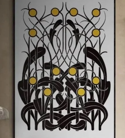 Decorative wall art featuring an abstract pattern of black leaf and plant shapes with yellow circular accents.