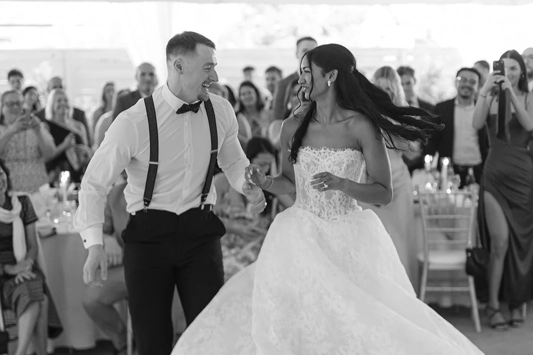 A bride and groom sharing a dance at their wedding reception, surrounded by seated guests.
