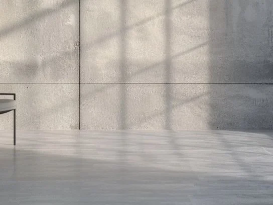 Empty room with concrete walls and floor, sunlight casting shadow grid patterns