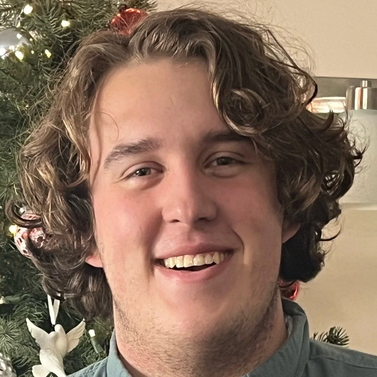 Thomas Lefebvre is smiling into the camera. he has curly brown hair